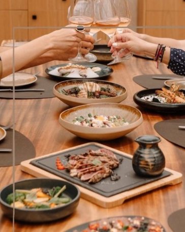 Sharing plates and wine on a timber table